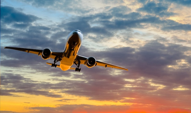 L'aereo va in decollo al tramonto sullo sfondo del cielo nuvoloso