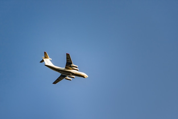 The plane is flying in the blue sky.