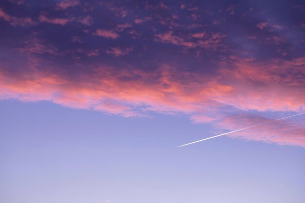 Photo a plane is flying over a pink and purple sky