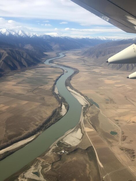 Photo a plane is flying over a river and mountains