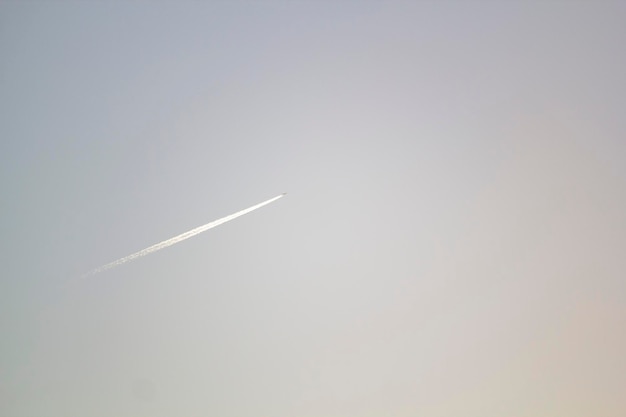 A plane is flying in the sky with a white streak in the sky.