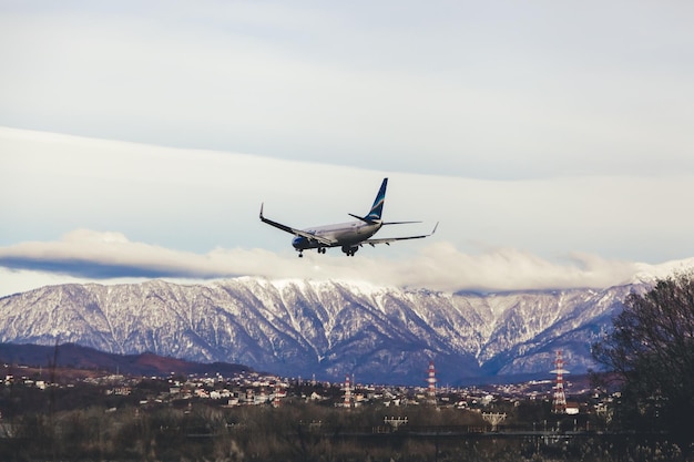 Самолет приземляется в аэропорту, горы в снегу на заднем плане
