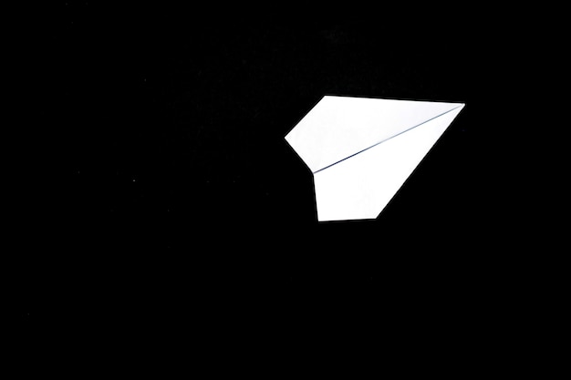 Photo a plane made of paper on a black.