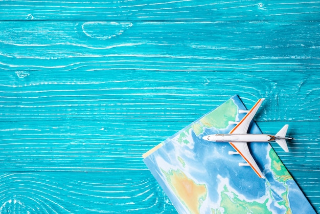 Plane and map located on blue wooden background