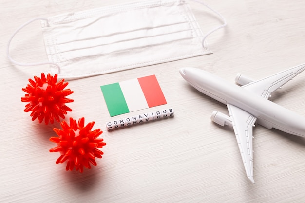 Plane model and face mask and flag Italy. Coronavirus pandemic. Flight ban and closed borders for tourists and travelers with coronavirus covid-19 from Europe and Asia.