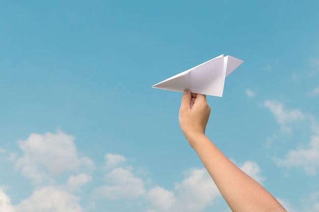 plane paper in children hand and blue sky