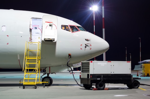 Plane parked at the airport at night, view nose cockpit.