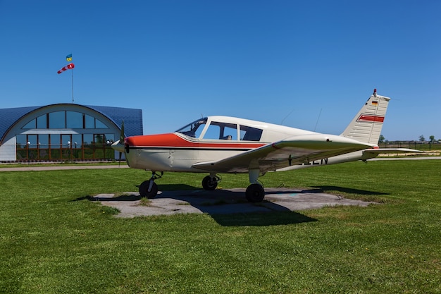 飛行機パイパーチェロキーは晴れた日に緑の芝生の上に立っています小さなプライベート飛行場