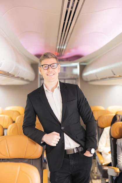 In the plane there is a young passenger portrait of a man standing in an airplane aisle