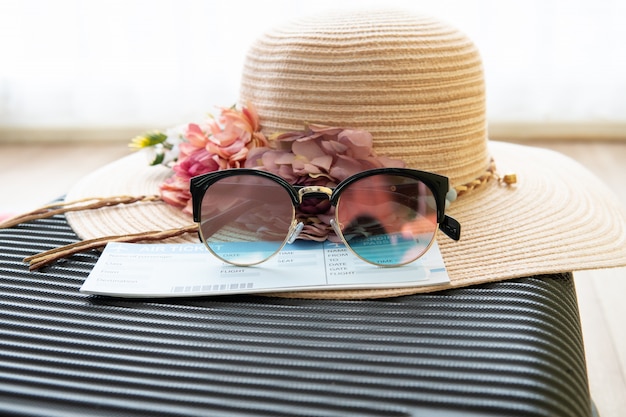 비행기 티켓, 태양 안경, 여자 모자는 수하물, 여름 시간 및 휴가 개념에 있습니다.