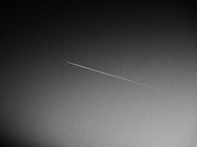 The plane and the trail in the sky is black or gray abstract\
background on a space or aero theme increased graininess light\
gradient