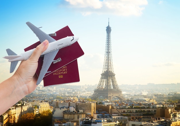 Photo plane travel concept, hand holding passports with plane, paris france cityscape in background