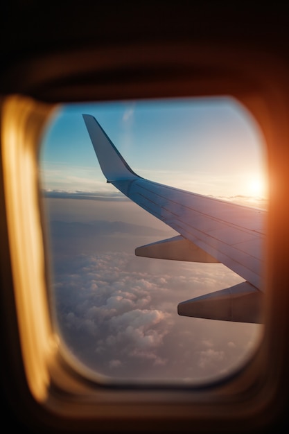 Plane window view of clouds and islands surrounded by sea and airplane wing. Traveling 