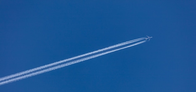 飛行機の後ろに白い痕跡 テキスト用の表示スペースの下の青い空背景バナー