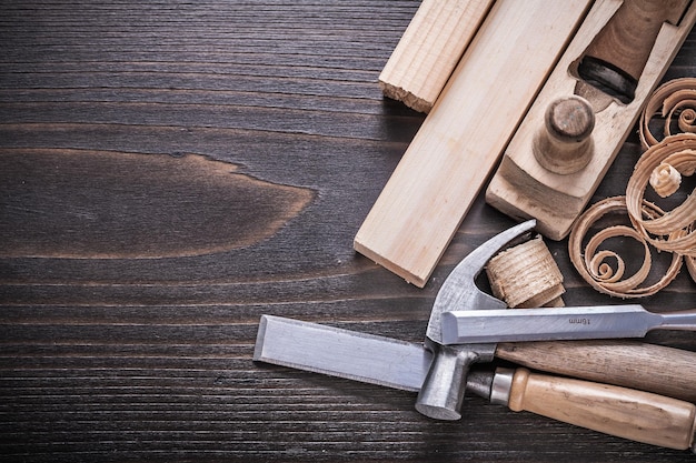 Planer claw hammer metal chisels wooden studs and curled shavings on vintage wood board construction concept