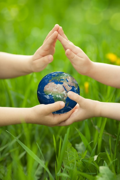 Planet Earth in childrens hands against green spring background Ecology concept Elements of this image furnished by NASA