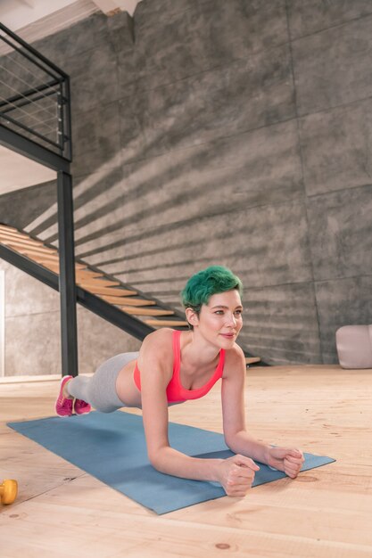 Plank after yoga. Fit young appealing woman with short hair cut doing morning plank after yoga