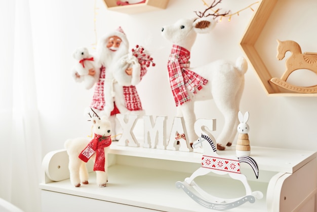 Plank met kerstfiguren santa en deer in kinderkamer. kerst interieur van de kinderkamer