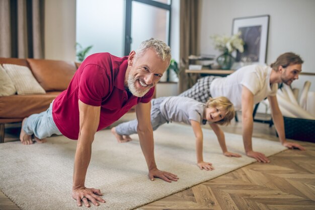 In plank. Two men and their son standing in plank and smiling