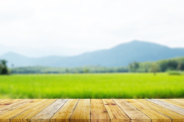 Foto plank van bruin houten plank bord met wazig groene rijst veld boerderij met berg en hut natuur.