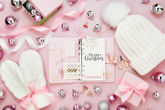 Planner mockup with Warm winter clothes and Christmas decor. Arrangement in pastel pink colors.