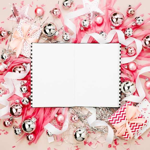 Planner with Christmas balls, gifts, ribbons,  and decorations in  pink colour with copy space for text. Holiday Background.  Flat lay, top view