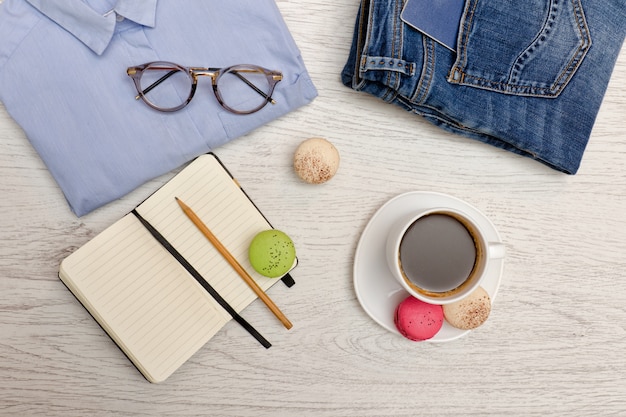 Planning affairs. Blue shirt, jeans with a passport, notebook and cup of coffee. Fashion concept. Top view