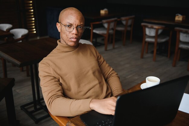 Planning The Day. Calm black student writing his lesson schedule in notebook, sitting in modern bar, empty space