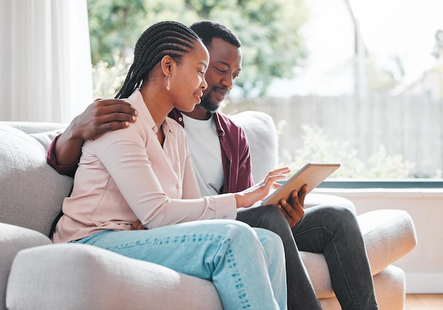 Planning for the days to come. Shot of a young couple relaxing at home using a digital tablet.