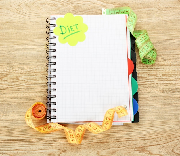 Planning of diet Notebook measuring tapes and pen on wooden table