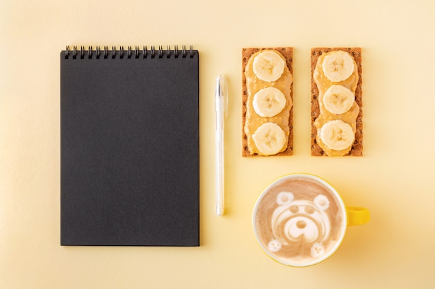 Photo planning during breakfast with cappuccino and crisp grain crackers with nut butter on yellow