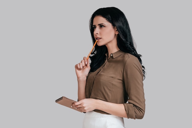 planning her day. thoughtful young woman in smart casual wear touching lip with pencil 