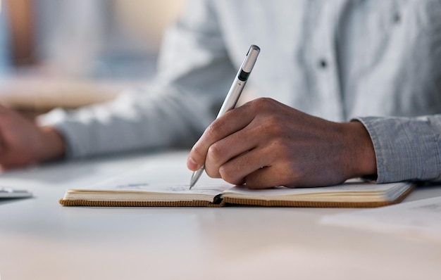 Pianificazione e produttività vanno di pari passo inquadratura di un uomo d'affari irriconoscibile che scrive su un taccuino durante una tarda notte di lavoro