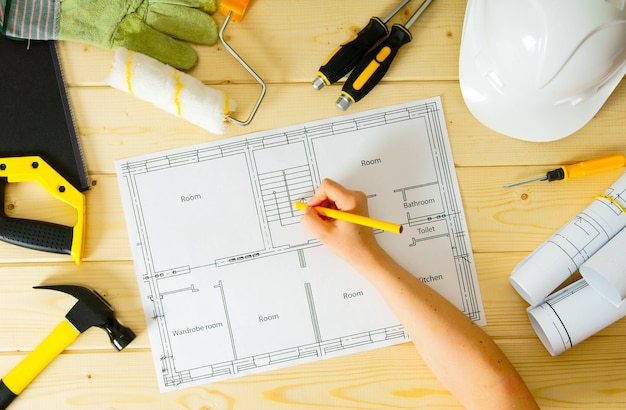 Planning of repair of the house. Repair work. Drawings for building, women hand, saw and others tools on wooden background.