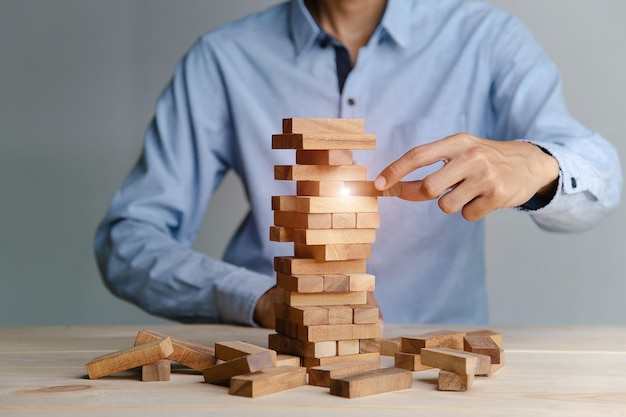 Planning risk and strategy in business businessman placing\
wooden block on a tower