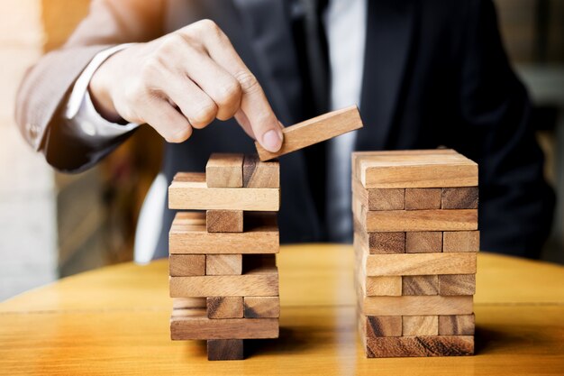 Strategia di pianificazione, rischi e ricchezza nel concetto di business, uomo d'affari e gioco d'azzardo che mette blocco di legno su una torre