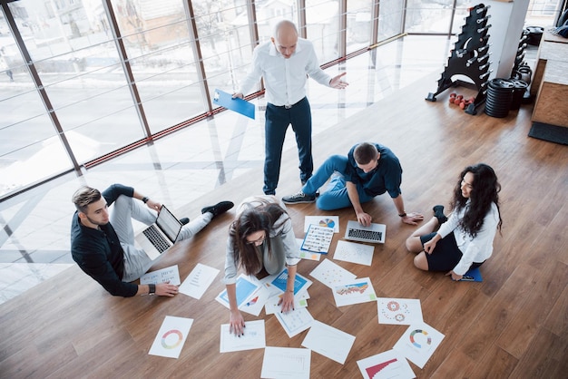 Planning strategy together Business team looking at papers on floor in search of one idea Cooperation corporate achievement and teamwork concept