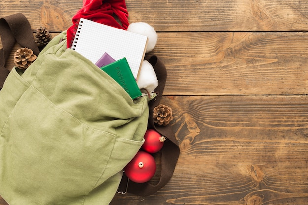 Planning for travel concept. Backpack with santa claus hat, passports and notepad with blank pages and Christmas decorations on wooden table top view