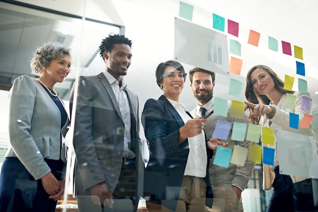 Planning with purpose and positivity Shot of a group of businesspeople brainstorming on a glass wall in an office