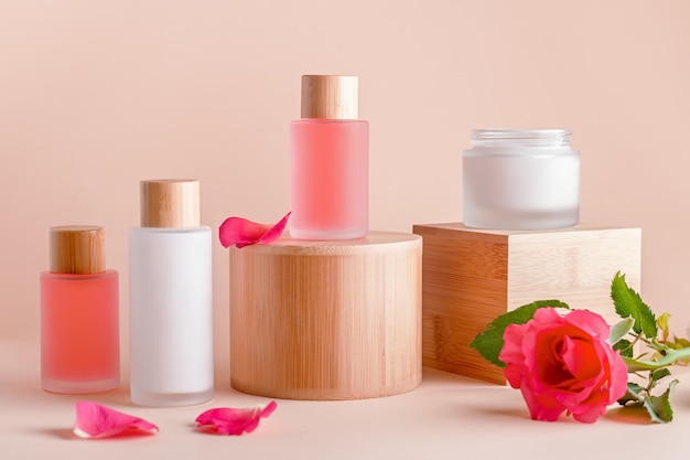 Cosmetici alla rosa a base vegetale su supporti o alzate con fiori di rosa natura morta concetto di prodotti di bellezza organici naturali per la cura della pelle e il trattamento di bellezza