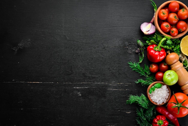 Plantaardige achtergrond verse tomaten, paprika, uien en peterselie op tafel bovenaanzicht op een zwarte achtergrond vrije ruimte voor tekst