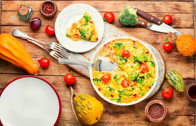 Plantaardige braadpan met broccoli, tomaat en pompoen op oude houten tafel. Frittata