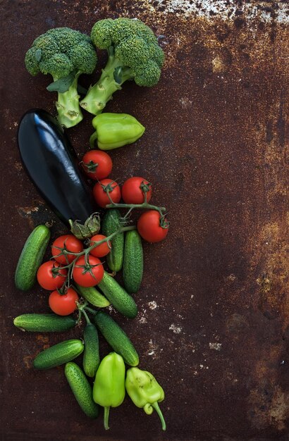 Plantaardige mix van tuinkerstomaten, komkommers, paprika's, aubergines, broccoli op roestige metalen grunge achtergrond bovenaanzicht