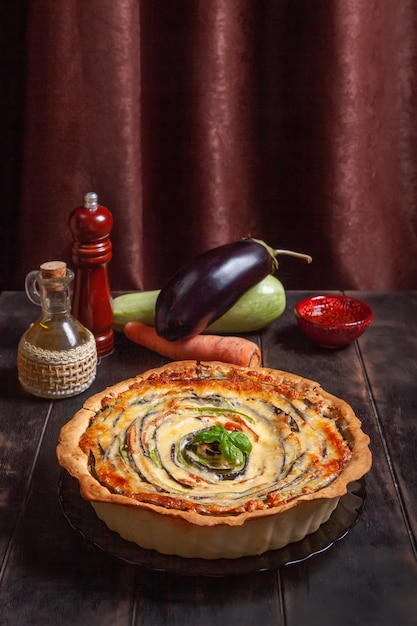 Plantaardige spiraal taart met courgette, aubergine, wortel op houten achtergrond.