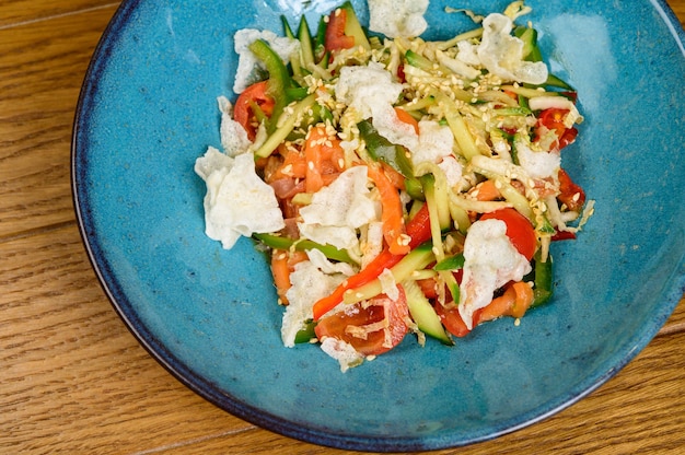 Plantaardige vegetarische salade met tomaten, paprika en uien op houten tafel. Gezonde salade met verse rijpe zomergroenten