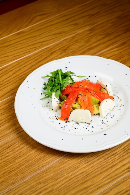 Plantaardige vegetarische salade met tomaten, paprika en uien op houten tafel. Gezonde salade met verse rijpe zomergroenten