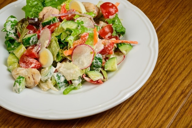 Plantaardige vegetarische salade met tomaten, paprika en uien op houten tafel. Gezonde salade met verse rijpe zomergroenten