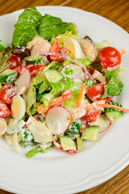 Plantaardige vegetarische salade met tomaten, paprika en uien op houten tafel. Gezonde salade met verse rijpe zomergroenten