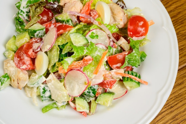 Foto plantaardige vegetarische salade met tomaten, paprika en uien op houten tafel. gezonde salade met verse rijpe zomergroenten