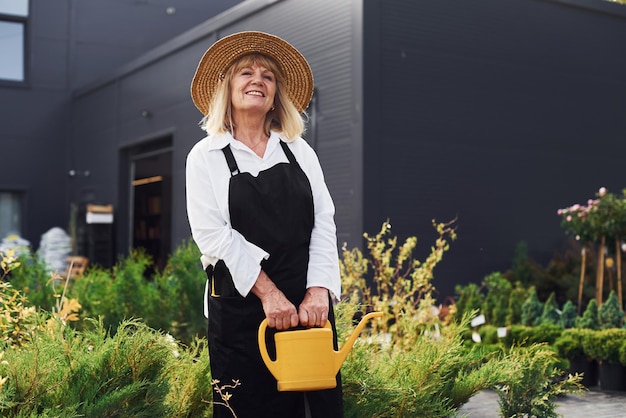 Planten water geven Senior vrouw is overdag in de tuin